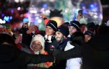 Le biathlète Martin Fourcade pose pour des selfies avec d'autres athlètes et volontaires de la cérémonie de clôture à Pyeongchang, le 25 février 2018