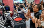 Des robots exécutent différentes tâches devant des visiteurs lors de la World AI Conference (WAIC), le 26 juillet 2025 à Shanghai   
