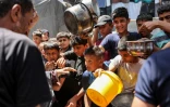 Des enfants font la queue avec des récipients pour recevoir de la nourriture dans une cuisine gérée par l'agence de l'ONU pour les réfugiés palestiniens (Unrwa), dans le camp de Jabalia dans le nord de la bande de Gaza, le 13 juin 2024