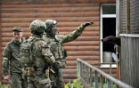 Un soldat russe lève la main pour attirer l'attention d'un ours en cage, au zoo de Marioupol, le 18 mai 2022 en Ukraine