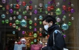 Un passant masqué devant la vitrine décorée pour Noël d'un magasin fermé pour cause de virus à Londres le 26 novembre 2020