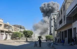 Des Palestiniens observent la fumée qui se dégage après des frappes israéliennes sur un camp de déplacés improvisé dans le centre de la ville de Gaza, le 23 mars 2025