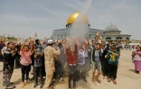Des fidèles musulmans priant sur l'esplanade des Mosquées à Jérusalem-Est se font asperger d'eau pulvérisée par des hommes juchés sur des conteneurs pour les rafraîchir, en raison de la forte chaleur, le 31 mai 2019 