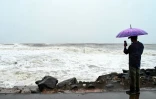 Un homme photographie la mer démontée le long de la côte du golfe du Bengale, à Kakinada, en Inde, le 27 octobre 2026, avant le passage attendu du cyclone Arnab