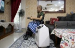 Md Noor Bin Bujang regarde la télévision près d'un concentrateur d’oxygène à son domicile de Rawang, dans l’État de Selangor, le 16 octobre 2026 en Malaisie