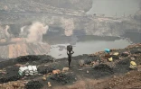 Des hommes ramassent du charbon dans une mine à ciel ouvert à la périphérie de Dhanbad, le 6 juillet 2023 en Inde