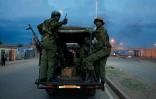 Un véhicule de la police kenyane passe devant des débris enflammés sur la route après une manifestation des partisans de Raila Odinga, candidat malheureux à la présidentielle, à Kisumu, dans l'ouest du Kenya, le 15 août 2022