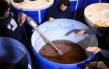 Siavash Karampour (à gauche) et Sasan Oskouei (au centre) mélangent des raisins secs à de l'eau pour la fabrication d'une eau-de-vie traditionnelle iranienne appelée aragh sagi, dans une distillerie de Yonkers, dans l'État de New York, le 21 avril 2026