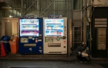 Un homme assis à côté de distributeurs automatiques, le 13 avril 2026 à Tokyo