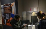 Les archéologues Murat Türkteki, à gauche, et Deniz Sari, à droite, observent un pain carbonisé vieux de 5.000 ans exposé au musée archéologique d'Eskisehir, en Turquie, le 23 mai 2025