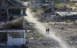 Des Palestiniens marchent près de bâtiments détruits, le 14 octobre 2025 dans la zone d'al-Zahra dans la bande de Gaza