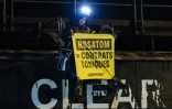 Un militant tient une banderole "Rosatom = contrats toxiques" lors d'une opération de Greenpeace visant à bloquer le cargo Mikhail Dudin à Dunkerque,  le 2 mars 2026 dans le Nord