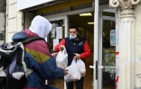 Un bénévole donne des sachets de nourriture à un homme au Noga, un restaurant social de Marseille, le 10 décembre 2020