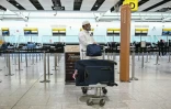 Un homme et ses bagages devant le comptoir d'enregistrement fermé de la compagnie aérienne émiratie Etihad, le 1er mars 2026 à l'aéroport Heathrow de Londres 