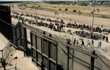 Des migrants attendent devant le mur frontalier américain, le 10 mai 2023 à El Paso, au Texas