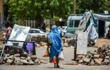 Une Soudanaise passe entre des barricades faites de pierres et de briques près du sit-in organisé par les manifestants soudanais devant le QG de l'armée à Khartoum, le 14 mai 2019