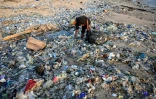 Un homme ramasse des déchets recyclables pour les revendre au milieu des ordures échouées sur la plage de Kedonganan, le 19 mars 2024 sur l'île indonésienne de Bali