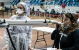 Une femme souffle dans un instrument en expérimentation qui doit permettre de dépister le virus du Covid-19, le 8 avril 2021, au Palais des sports de Lyon