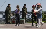 Des enfants jouent dans une rue de Melitopol à côté de soldats russes, le 1er mai 2022 en Ukraine