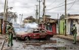 Des policiers à côté d'une voiture brûlée lors de heurts avec des manifestants, le 19 juillet 2023 à Nairobi, au Kenya