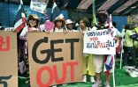 Des manifestants tiennent des pancartes appelant la Première ministre thaïlandaise Paetongtarn Shinawatra à démissionner, lors d'un rassemblement devant le palais du gouvernement, le 19 juin 2025 à Bangkok