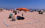 Sur une place à Gandia, près de Valence (Espagne), un homme a matérialisé sur le sable un espace pour respecter les distances sociales, le 1er juillet 2020