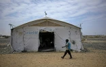 Un élève passe devant une tente servant d'école dans un camp de personnes déplacées par la guerre, près de Port-Soudan, le 26 avril 2026 au Soudan