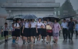 Des étudiantes marchent sous la pluie pour aller se recueillir devant le mausolée du fondateur du régime Kim Il-Sung, le 27 juillet 2017 à Pyongyang