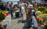 Un homme avance à genoux en tenant une statue de la Santa Muerte dans une rue du quartier de Tepito, le 1er octobre 2020 à Mexico