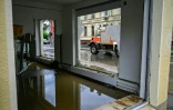 Un camion de pompiers passe devant un bâtiment inondé et aux vitres brisés par les fortes intempéries à Dahl, près de Hagen, dans l'ouest de l'Allemagne, le 15 juillet 2021