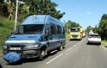 Un véhicule des forces de l'ordre escorte des camions de l'équipement pour dégager un barrage, le 24 mai 2024 à Nouméa