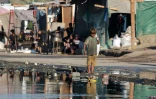 Un jeune Palestinien marche pieds nus près d'eaux usées stagnantes à Deir el-Balah, dans le centre de la bande de Gaza, le 19 juillet 2024
