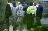 Des membres des services d'urgence portent des combinaisons de protection , le 10 mars 2018, dans un cimetière de Salisbury, dans le sud de l'Angleterre où sont enterrés la femme et le fils de l'ancien agent russe Sergueï Skripal, empoisonné avec sa fille par un agent innervant.
