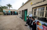 Des élèves se tiennent devant les salles de classe d'une école située dans le centre de l'Irak, le 10 mars 2024