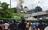 Des habitants regardent un bâtiment incendié lors d'émeutes à Honiara, le 24 novembre 2021 aux Iles Salomon