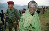 Un réfugié tutsi attend sous la pluie près d'un parachutiste français le 29 juin 1994 dans le camp de réfugiés de Nyarushishi où 8.000 Tutsi ont été rassemblés sous la protection des forces françaises