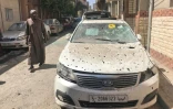 Un homme passe à côté d'une voiture criblée d'éclats le 17 avril 2019 à Tripoli, visée la veille par des tirs de roquettes