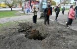 Des habitants regardent un trou provoqué par une bombe dans les faubourgs nord de Kharkiv, le 22 avril 2022
