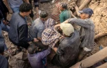Des secouristes bénévoles récupèrent un corps dans les ruines d'une maison effondrée, le 10 septembre 2023 à Imi N'Tala, dans le centre du Maroc 
