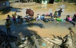 Des villageois lavent leurs vêtements dans une flaque d'eau après une crue soudaine qui a frappé leur village à Tukka, dans le district de Tapanuli central, province de Sumatra du Nord, le 3 décembre 2025