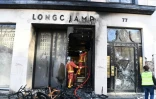Des pompiers éteignent un incendie dans un magasin Longchamp, lors des manifestations de "gilets jaunes", le 16 mars 2019 sur les Champs-Elysées à Paris