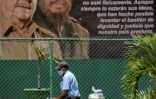 Un homme passe devant une affiche montrant les ex-présidents cubains Fidel et Raul Castro, à La Havane le 13 avril 2021