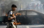 Un policier passe devant une voiture brûlée lors d'une manifestation contre la hausse du prix du diesel à Ribeirao das Neves au Brésil, le 25 mai 2018