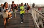 Une bénévole donne des instructions aux vacanciers de Lège-Cap-Ferret à leur arrivée à Arcachon par bateau, lors d'une opération d'évacuation de l'ensemble de la presqu'île du Cap-Ferret, dans le sud-ouest de la France, le 24 juillet 2026