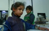 Des enfants syriens blessés attendent d'être soignés dans un hôpital de fortune, après des raids aériens du régime sur la localité de Douma, dans le fief rebelle de la Ghouta orientale, le 23 février 2018 