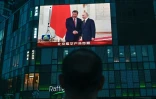 Les présidents russe Vladimir Poutine (d) et chinois Xi Jinping à Moscou sur un écran posé contre la façade d'un centre commercial à Pékin, le 8 mai 2025
