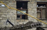 Un vieil homme regarde par une fenêtre endommagée par une explosion à Stepanakert au Nagorny Karabakh le 6 octobre 2020