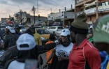 Une femme portant un t-shirt du président sortant du Cameroun, Paul Biya, est prise à partie par des chauffeurs de moto-taxis soutenant le candidat d'opposition Issa Tchiroma, à Yaoundé le 11 octobre 2025