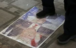 Un Iranien marche sur un portrait du président américain Donald Trump installé sur le sol de la ville-frontière de Zurbatiyah, en Irak, le 29 juillet 2026