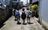 Des enfants sur un trottoir sec, en chemin pour l'école, sur l'île de Pugad, dans la province de Bulacan, le 7 juillet 2025 aux Philippines